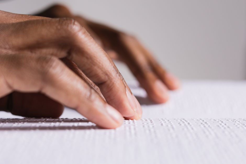 Hands touching and reading Braille text, highlighting tactile learning and accessibility.