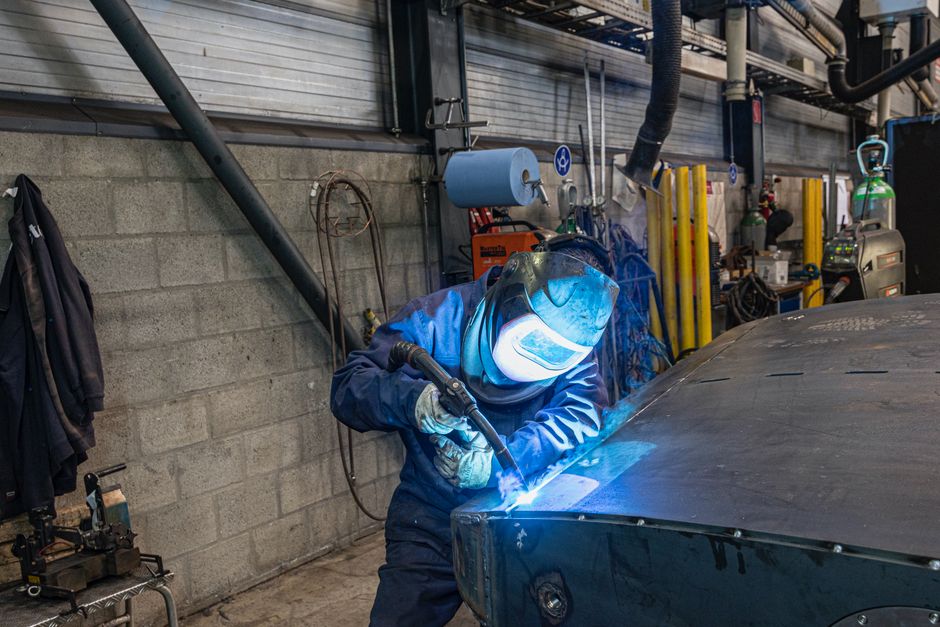 Skilled welder in protective gear welding metal in a workshop.