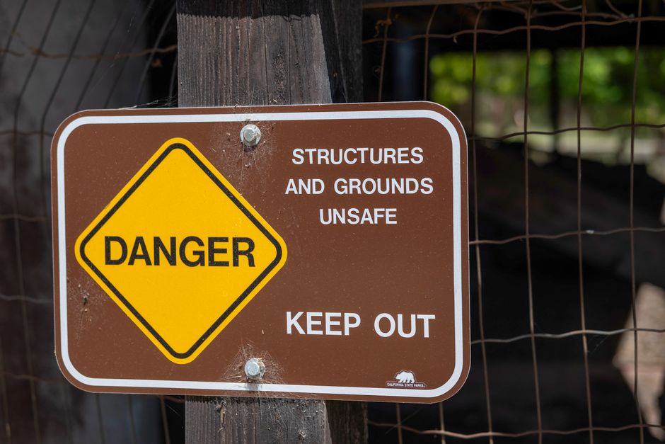 Danger sign warning about unsafe structures and grounds with keep out notice.