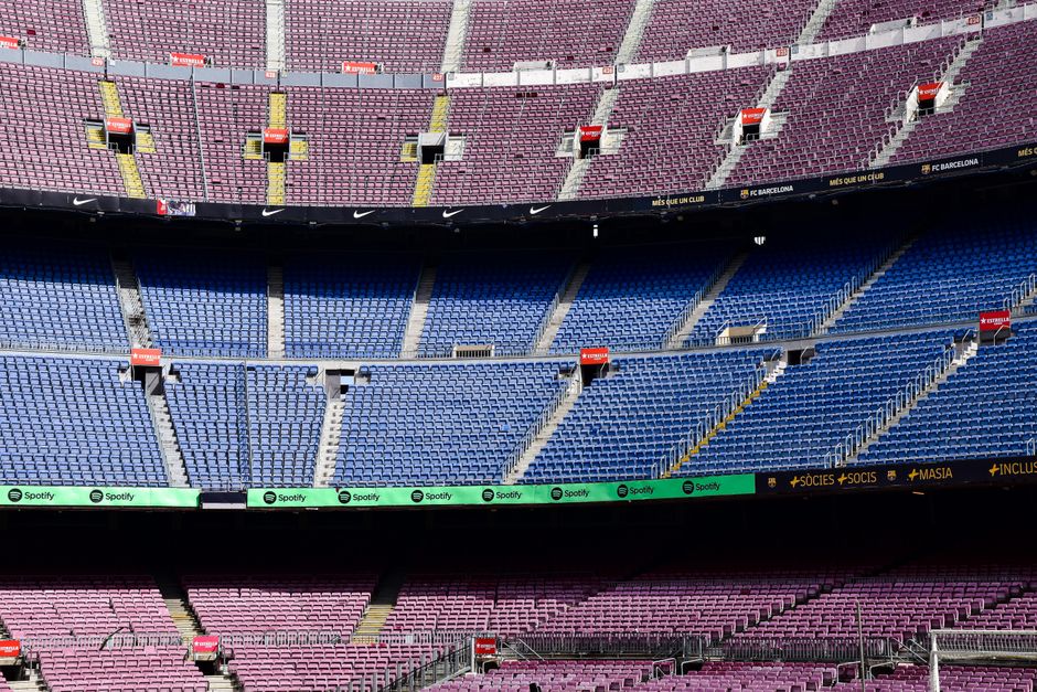 Wide-angle view of the empty stands at Camp Nou Stadium in Barcelona displaying vibrant seat colors.