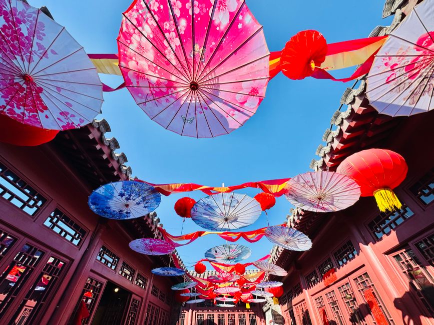Colorful parasols and lanterns hang over a traditional courtyard in Tianjin, China.