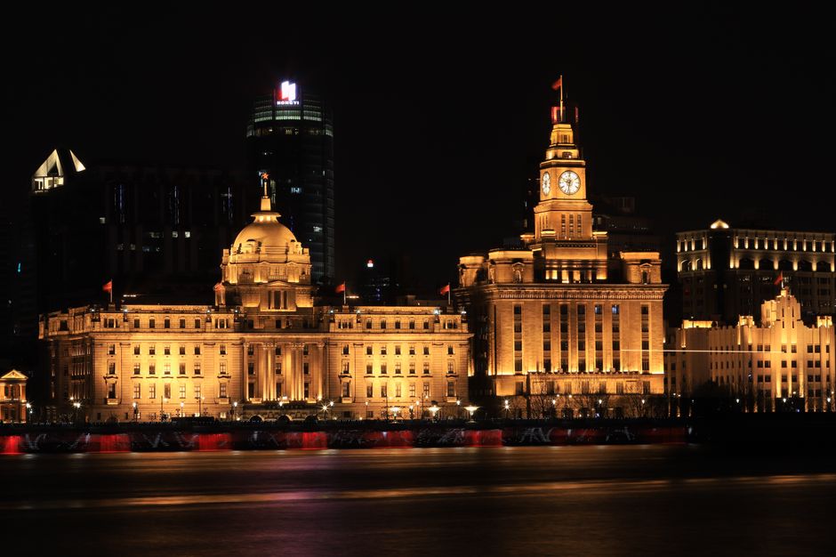 Illuminated night view of historic buildings along Shanghai Bund waterfront, China.