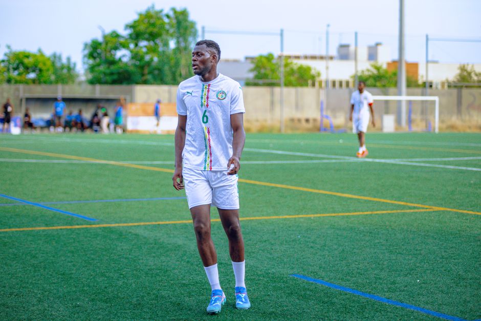 Soccer player in white kit on field, ready for action. Bright day outdoor sports scene.