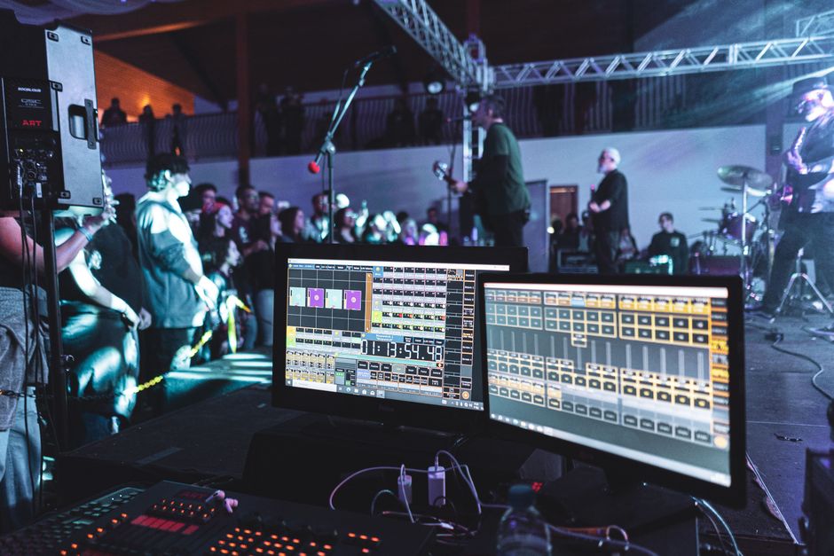 Live concert scene with sound engineering setup and band on stage.
