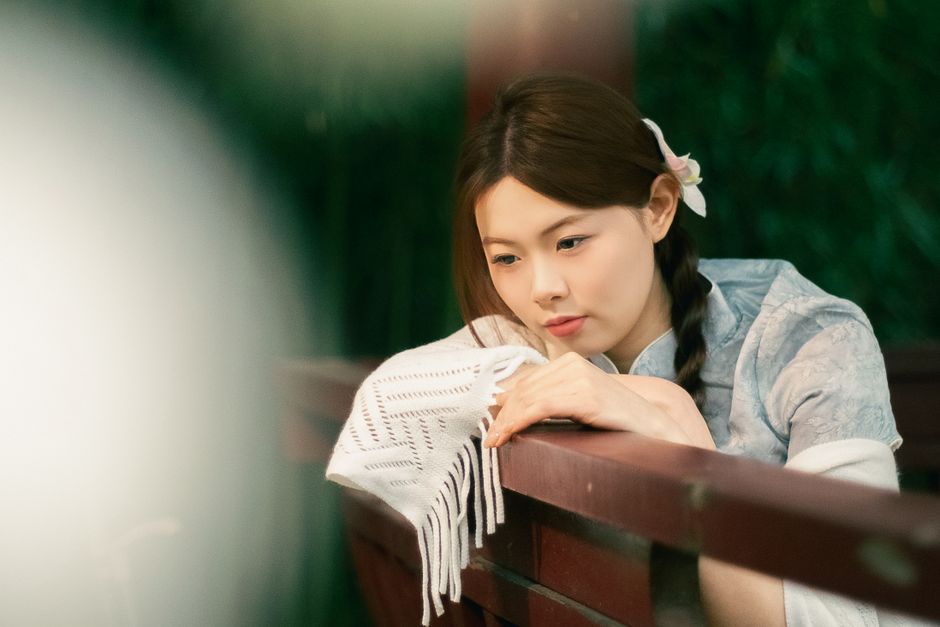 Woman in traditional attire reflects on a sunny day outdoors.