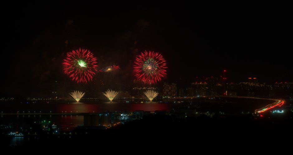Stunning fireworks illuminate the night sky over a vibrant cityscape, captured with beautiful reflection on the water.