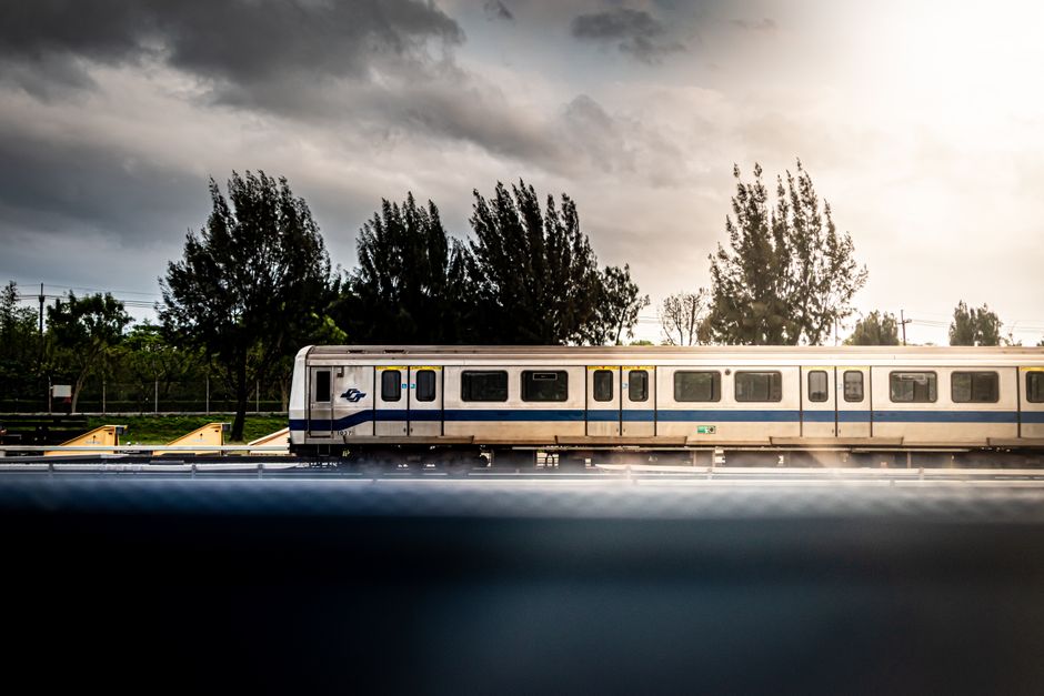A train under dramatic skies travels along a scenic railway line, highlighting modern transportation.
