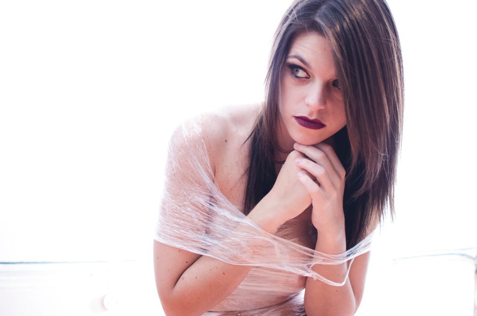 Portrait of a young woman wrapped in plastic looking thoughtful and pensive indoors.