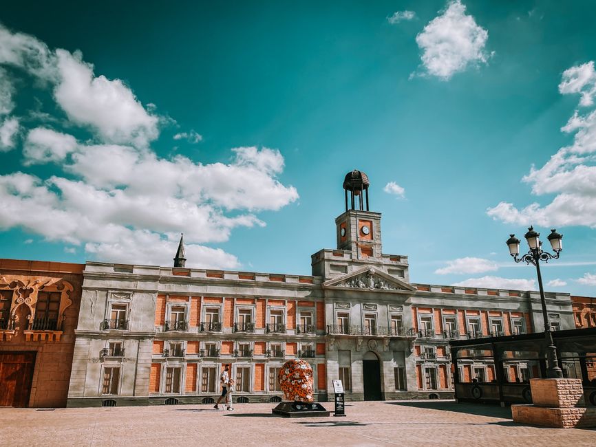 Vibrant facade of the iconic building at Puerta del Sol, Madrid, under a bright blue sky.
