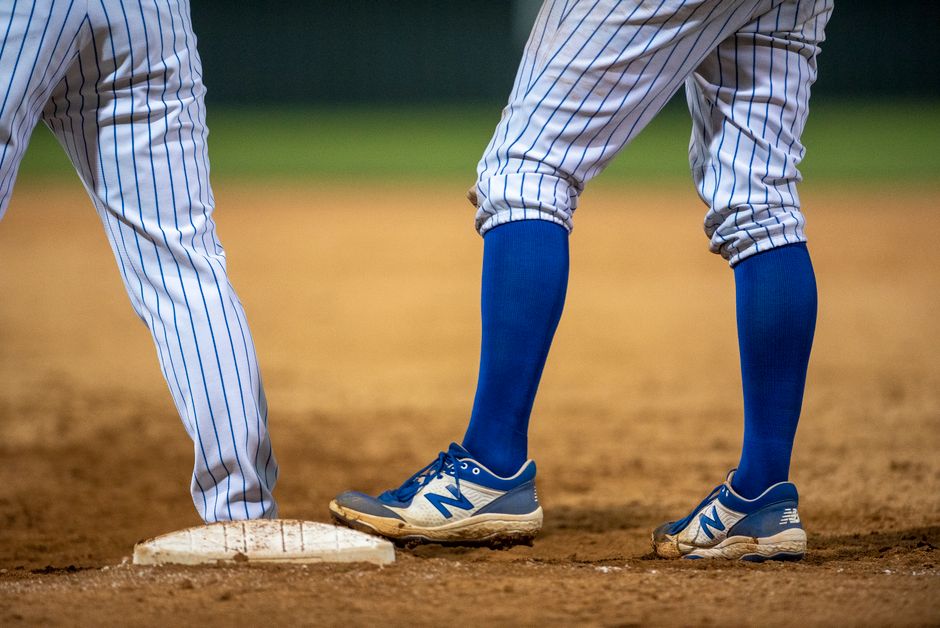 Close-up of baseball players wearing blue knee socks and sneakers at second base.