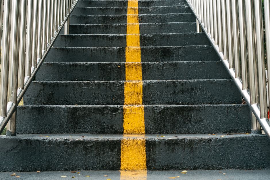 Close-up of urban staircase featuring a prominent yellow line and metal railings.