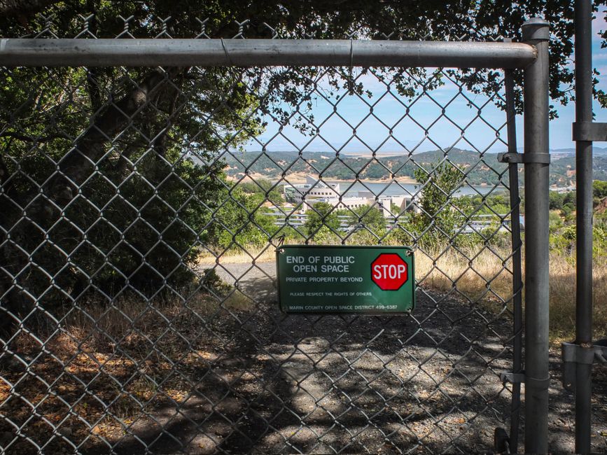 View through chain link fence with private property warning sign and natural landscape.