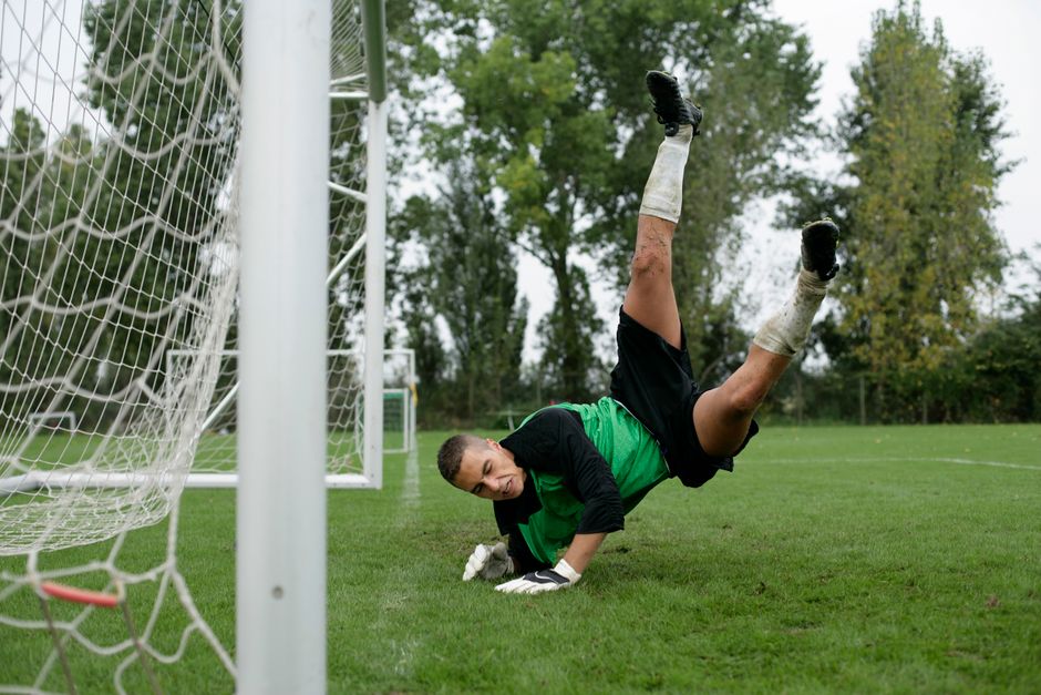 Soccer goalkeeper makes a dramatic save midair during a game.