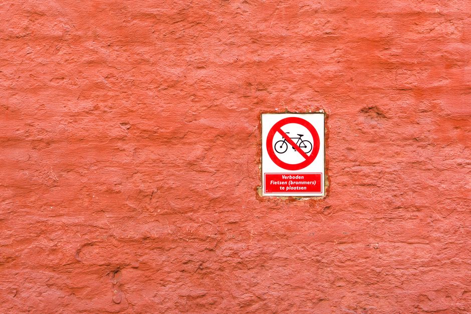 Prohibition sign against parking bicycles on a rustic red brick wall.