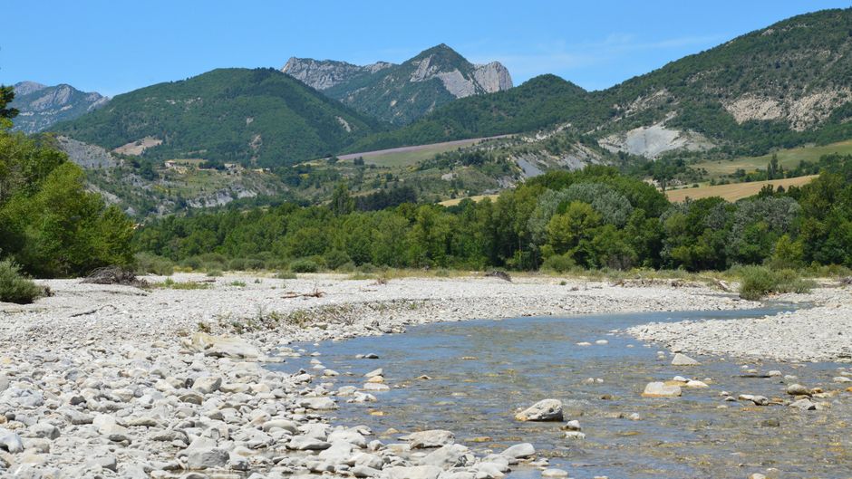 Peaceful mountain stream flowing through a picturesque valley with lush greenery.
