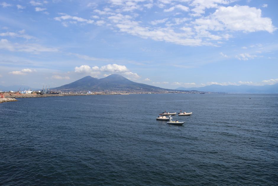 A stunning aerial view of Mount Vesuvius with boats sailing through the picturesque Bay of Naples.