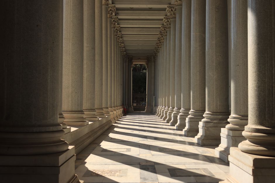 Elegant colonnade with light and shadows in Rome, Italy, highlighting ancient architectural beauty.