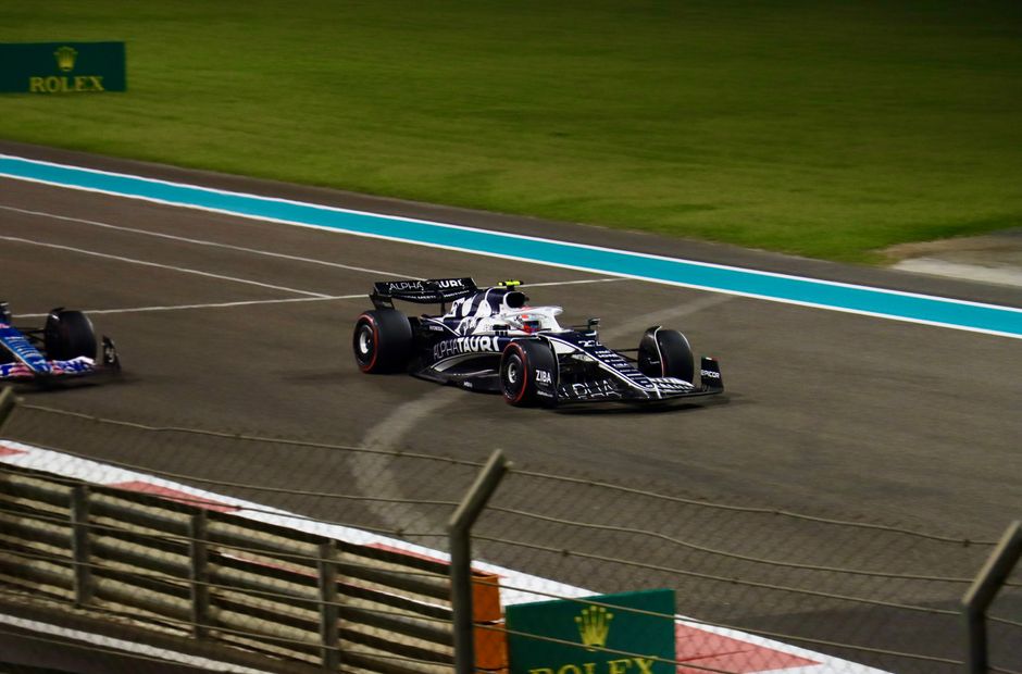 Formula 1 cars racing at night on the Yas Marina Circuit in Abu Dhabi.