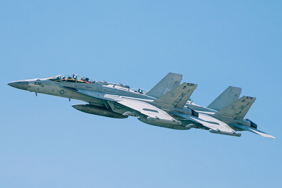 F/A-18 Super Hornets flying in formation in a clear blue sky over New York.