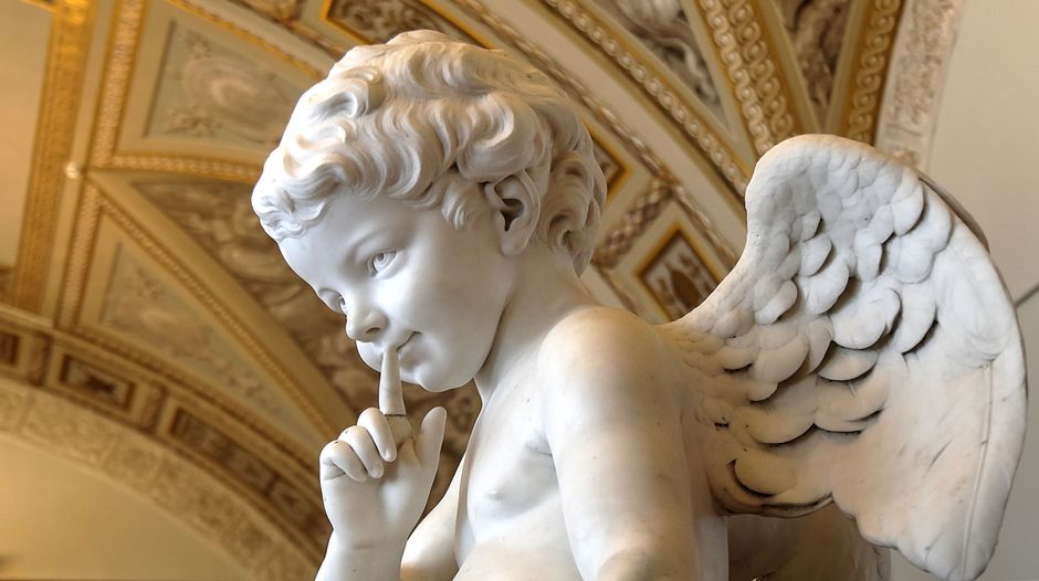 Majestic marble angel statue in an ornate museum interior.