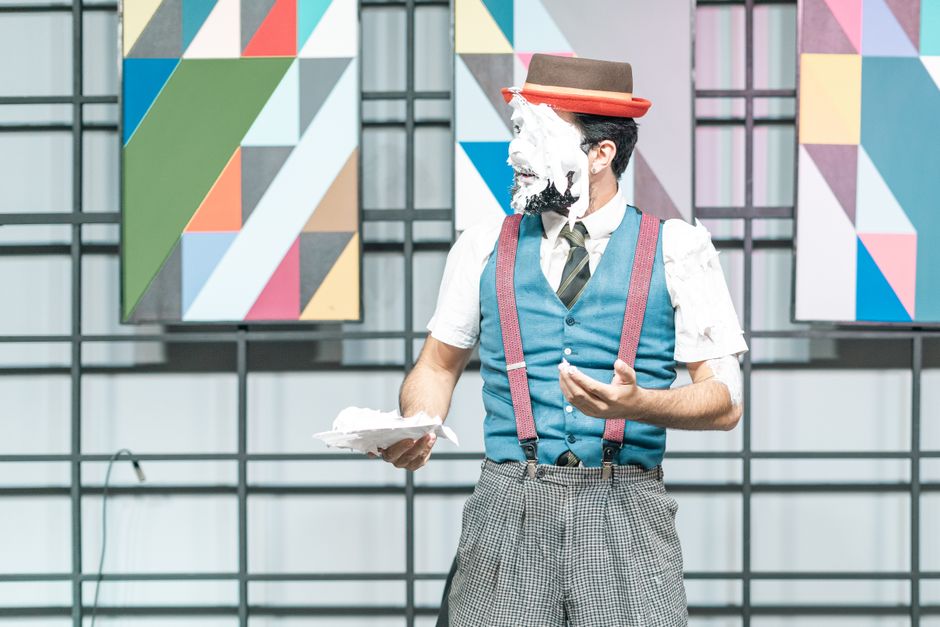 A clown with a pie-covered face on stage, showcasing comedic entertainment.