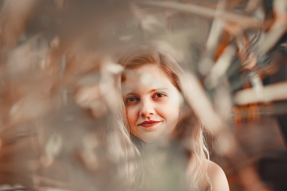 Artistic photo of a smiling blonde woman with blurred foreground, captured in São Paulo.