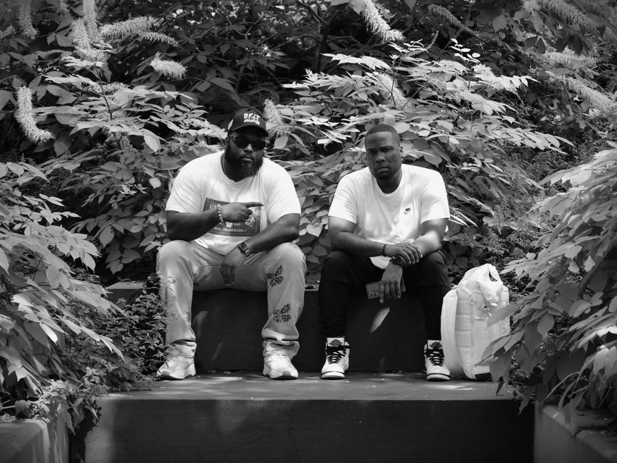 A black and white photo of two men sitting in a lush Chicago park, enjoying relaxation.