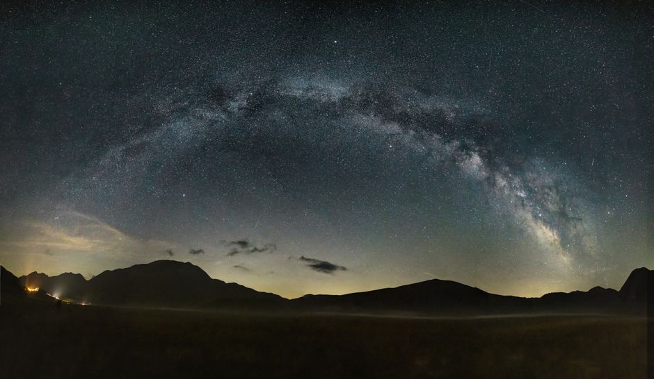 Capture of the Milky Way arching over Castelluccio's landscape at night.