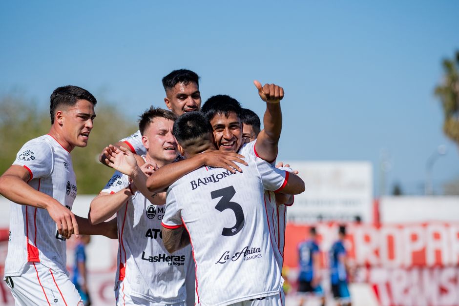 Group of young male soccer players celebrating a victory on the field.