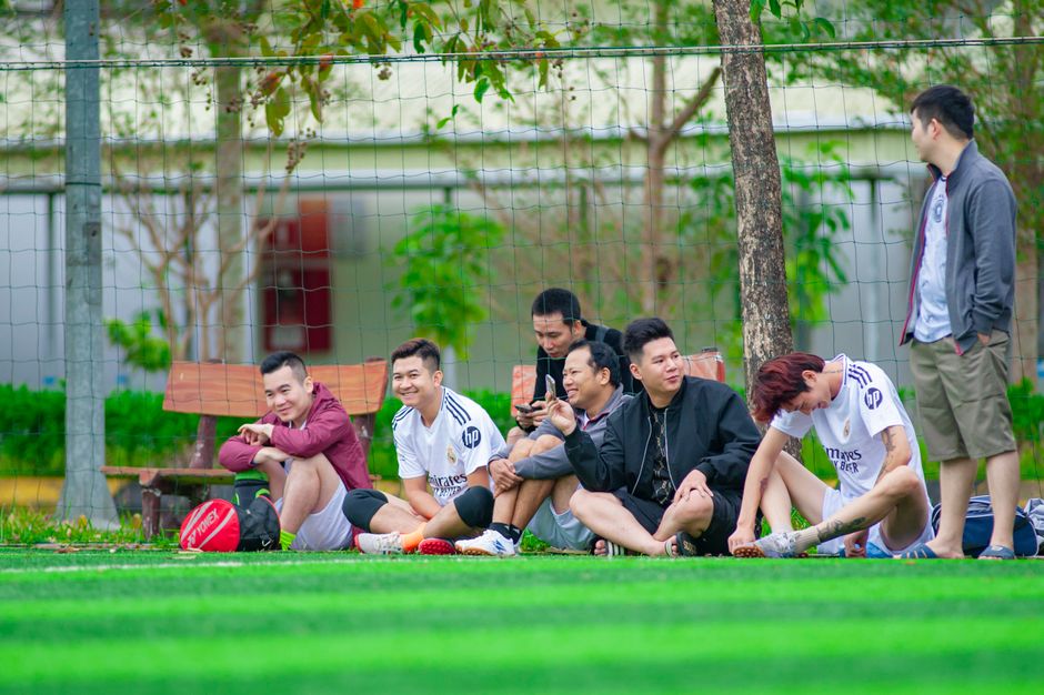 Group of friends relaxing at a football field in Hanoi, Vietnam, enjoying leisure time outdoors.