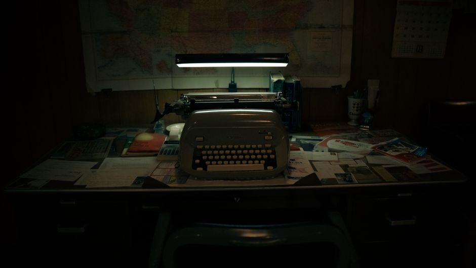 A classic office scene with a vintage typewriter on a cluttered desk under soft lighting.