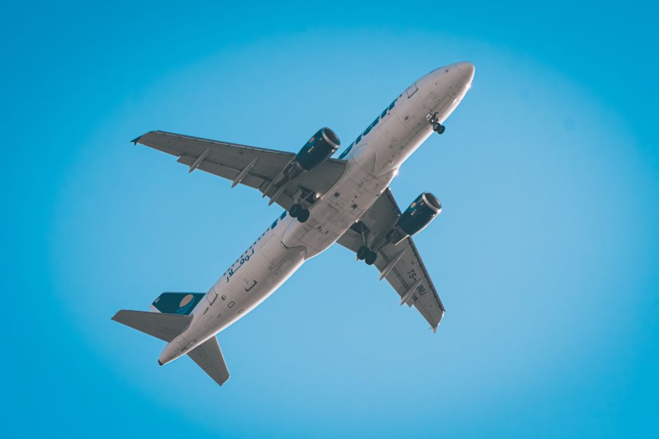 Commercial airplane flying overhead against a clear blue sky, showcasing travel and aviation.