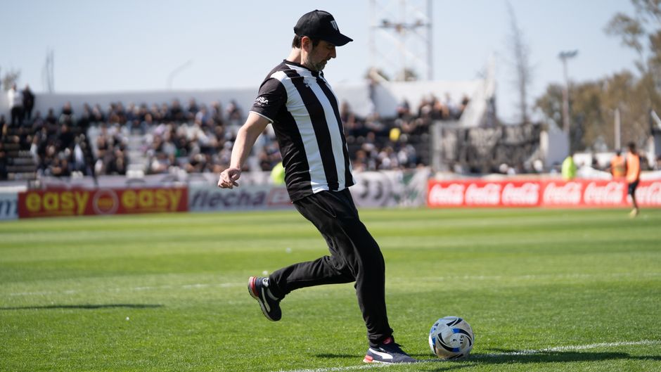 A male football player in action on a sunny day at a soccer stadium.