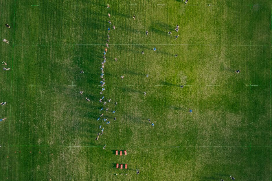 An aerial view of a group training session on a large soccer field, showcasing teamwork.