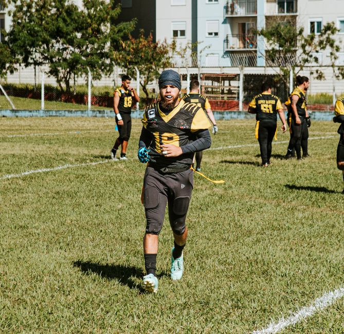 Football practice with athletes in black and yellow uniforms on a sunny outdoor field.