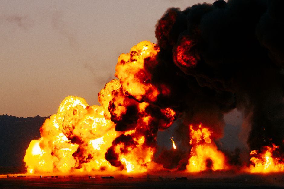 Intense fiery explosion with billowing smoke during twilight outdoors.