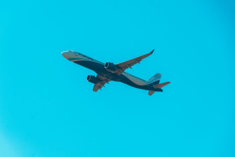 A commercial airplane soars through a clear, cloudless sky, symbolizing global travel and aviation.