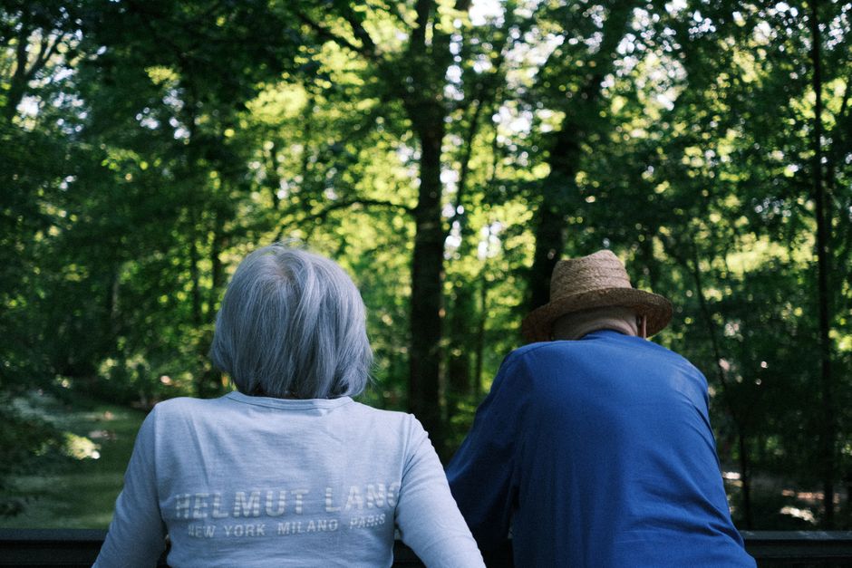 A senior couple sits in a lush park, enjoying a peaceful day outdoors in Munich.