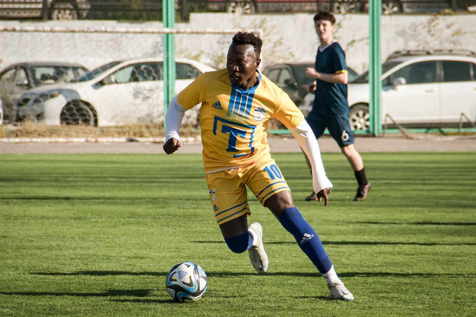 Exciting soccer match in Almaty, Kazakhstan, capturing a player in action on a sunny day.