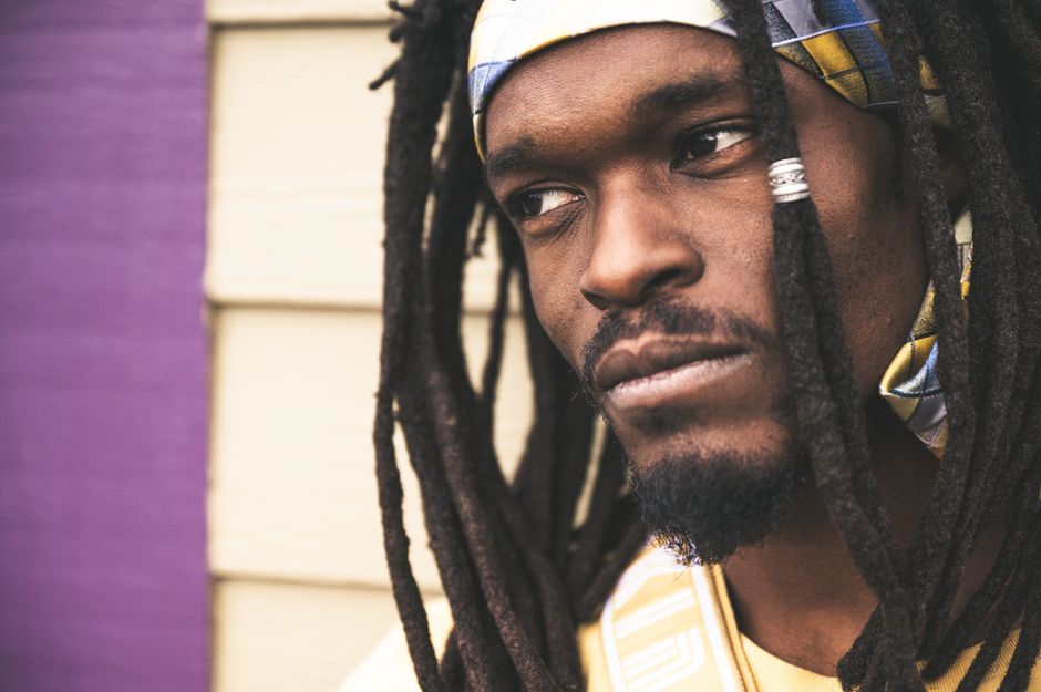 Close-up portrait of a man with dreadlocks wearing a colorful headband. Thoughtful expression.