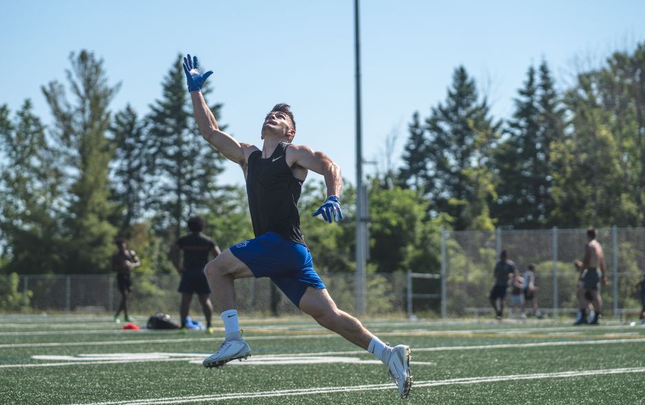 An athlete leaps to catch a ball on a sunny day, showcasing energy and determination on a sports field.