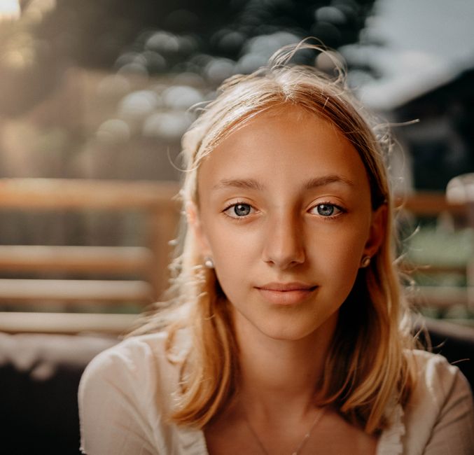 A serene portrait of a blonde girl with soft natural lighting and bokeh background.