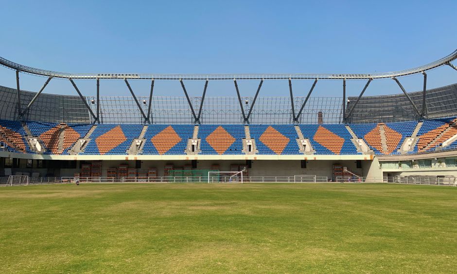 A wide view of an empty stadium in Ahmedabad, showcasing seating arrangements and green field.
