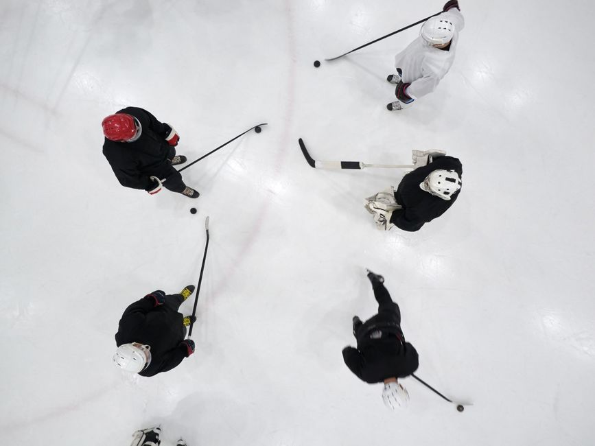 Top view of hockey players practicing on an indoor ice rink, geared up and ready for the game.