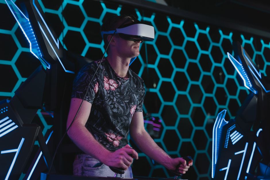 An adult male enjoying a virtual reality game in an arcade setting with futuristic elements.