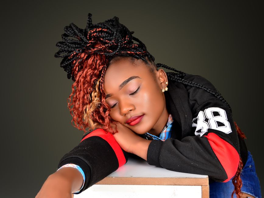 A relaxed woman with braided hair resting her head, captured in a studio setting.