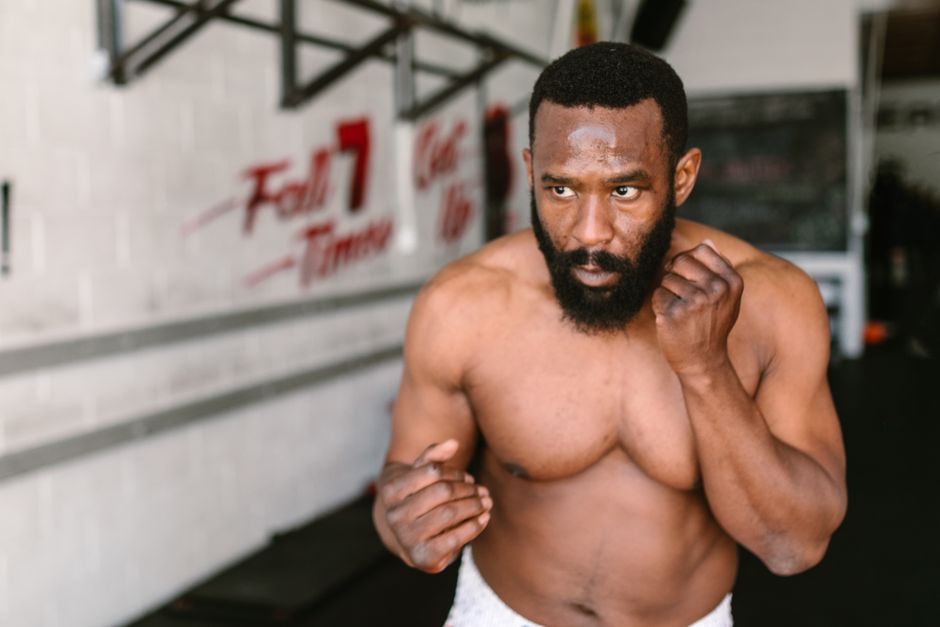 A fit, muscular man shadowboxing in an indoor gym, showcasing a healthy lifestyle.