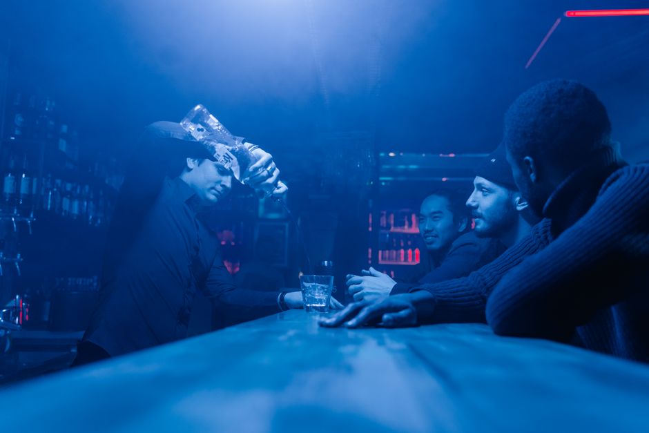 A bartender pours drinks for friends enjoying a night out at a club.