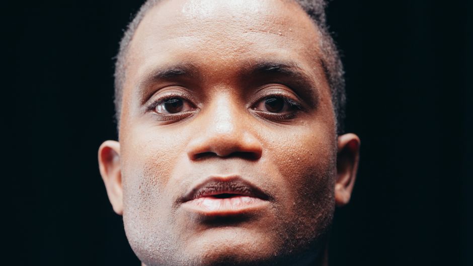 Close-up portrait of a man with a contemplative expression against a dark background.
