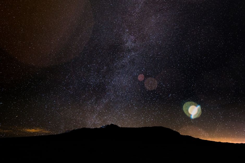 Capture the beauty of a starry night sky over a mountain silhouette, perfect for astronomy enthusiasts.
